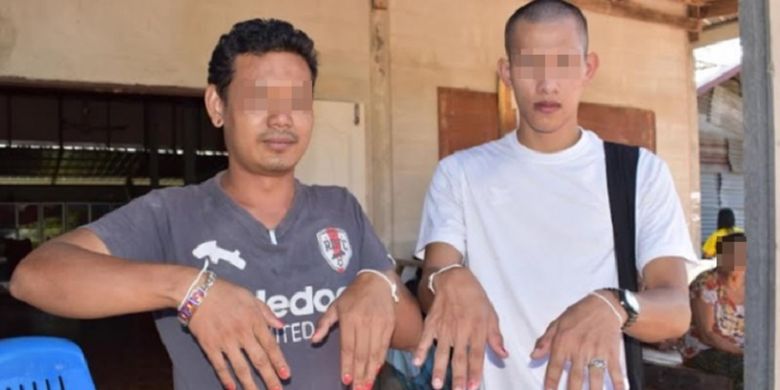 Dua pria dari desa Pu Hong, Thailand, menunjukkan kuku mereka yang telah diwarnai sebagai langkah pencegahan untuk mengusir hantu yang dianggap bertanggung jawab atas kematian lima warga dalam tiga pekan terakhir.