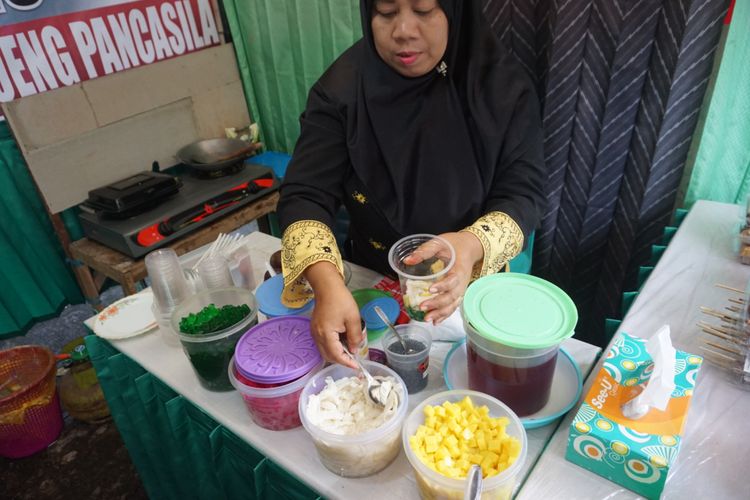 Bu Legi sedang membuat Es Tofu Pelangi dengan bahan baku dari tahu pada Festival Tahu Tempe di Jalan Kalilo Banyuwangi, Jawa Timur. Festival ini digelar mulai Jumat (9/2/2018) hingga Selasa (13/2/2018), dari pukul 15.00-22.00 WIB.