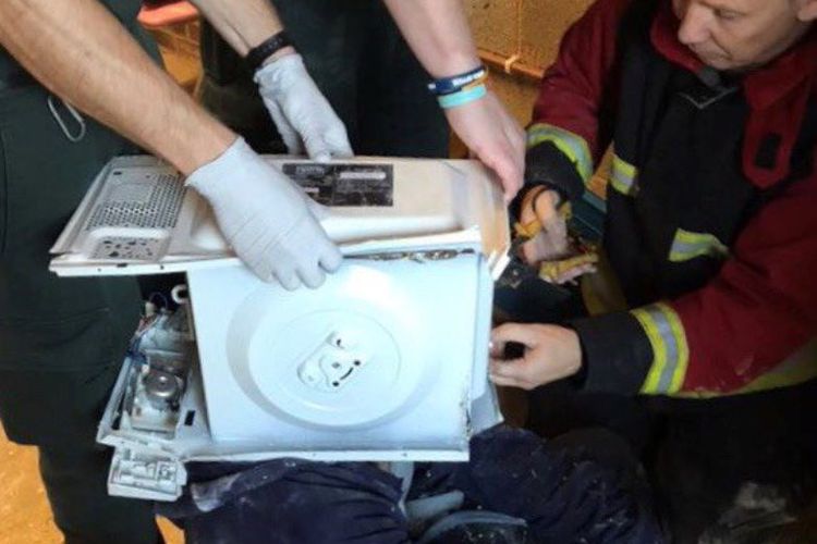 Petugas pemadam kebakaran West Midlands saat berusaha membebaskan seorang pemuda yang kepalanya tersangkut di dalam oven microwave, Rabu (6/12/2017).