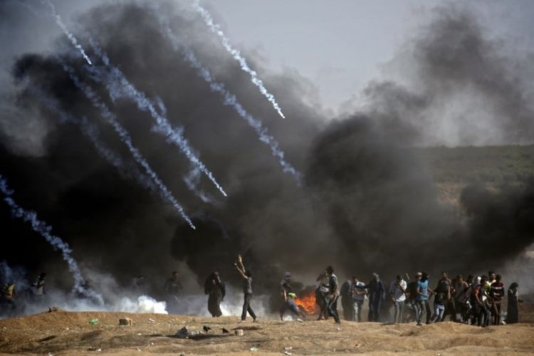 Gas air mata ditembakkan pada massa selama bentrokan dengan pasukan Israel di dekat perbatasan antara jalur Gaza dan Israel, di sebelah timur Kota Gaza pada Senin (14/5/2018). (AFP/Thomas Coex)