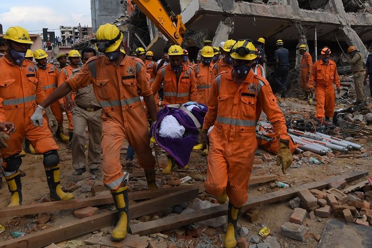 Petugas dari Pasukan Tanggap Bencana Nasional (NDRF) membawa jenazah korban yang ditemukan di lokasi runtuhnya gedung di Shah Beri, Greater Noida, Rabu (18/7/2018).