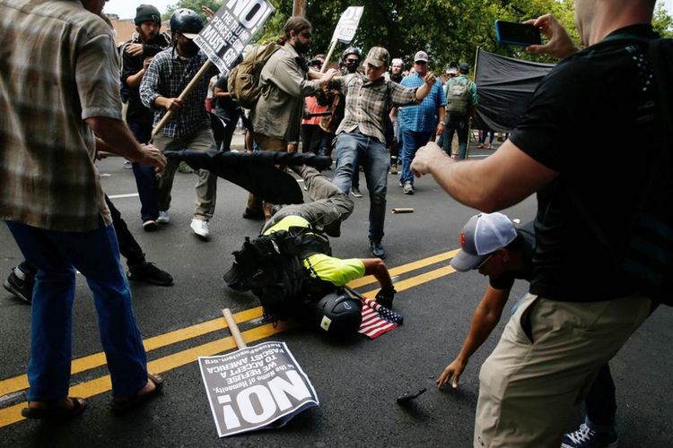 Seorang pria tersungkur ke jalan dalam bentrokan antar-demonstran pendukung dan penentang gerakan supremasi kulit putih di Kota Charlottesville, Virginia, AS, Sabtu (13/8/2017). 
