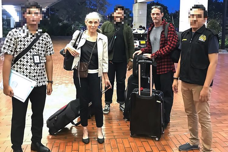 Michael Blanc dan ibunya, Helene Le Touzay dengan dikawal tiga petugas imigrasi berada di Bandara Internasional Soekarno-Hatta, Sabtu (21/7/2018) sebelum dipulangkan ke Perancis.| Indonesian Immigration Agency/AFP