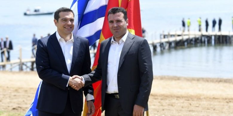 Perdana Menteri Macedonia Zoran Zaev (kanan) menyambut Perdana Menteri Yunani Alexis Tsipras (kiri) di tepi Danau Prespa dekat Otesevo Minggu (17/6/2018) dalam kesepakatan pergantian nama Macedonia menjadi Republik Macedonia Utara. (AFP/Maja Zlatevska)