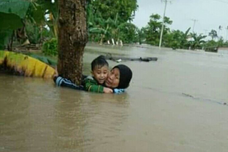 Nurjannah Djalil (70) saat menyelamatkan cucunya dengan berpegang pada pohon saat banjir bandang melanda Kabupaten Gowa, Sulawesi Selatan, Selasa (22/1/2019).