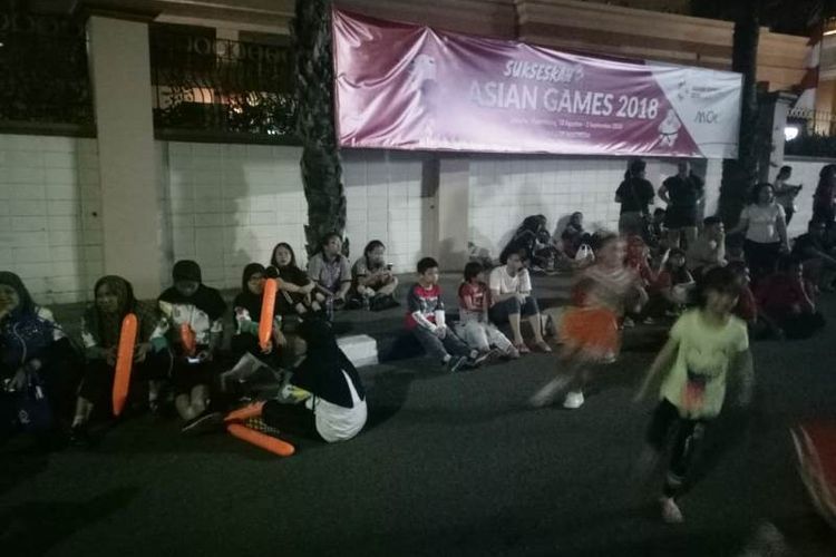 Warga dan para siswa yang bertugas menyambut obor Asian Games 2018 duduk-duduk di trotoar di depan Mall of Indonesia (MOI), Kelapa Gading, Jakarta Utara.