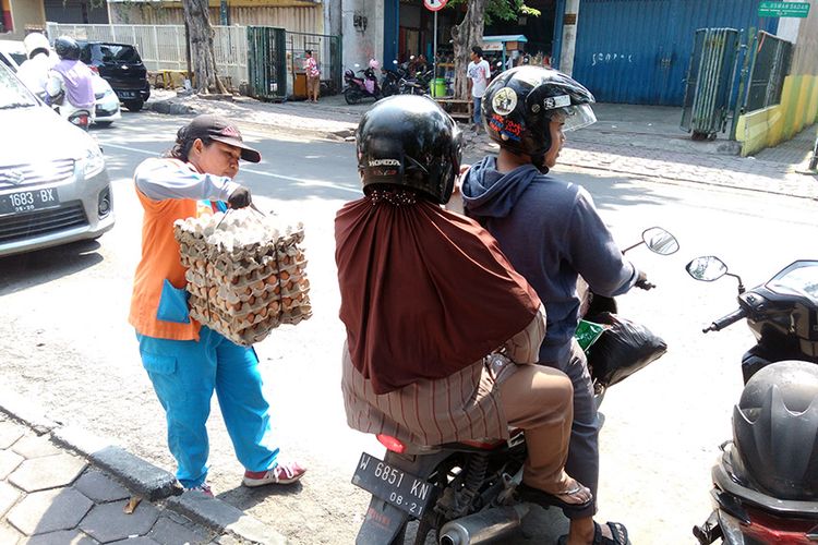 Dengan cekatan Maimunah (kiri) membantu mengangkat barang bawaan para pengunjung pasar.