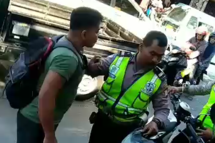 Sebuah video beredar di WhatsApp yang memperlihatkan perkelahian antara seorang petugas polisi lalu lintas dengan seorang pria berbadan kekar yang mengenakan kaus berwarna hijau.