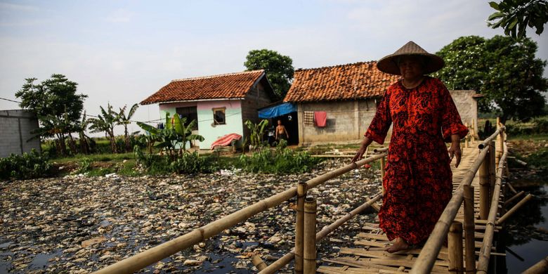 Warga melintas disamping sampah yang didominasi plastik di sepanjang Kali Pisang Batu, Desa Pahlawan Setia, Kecamatan Tarumajaya, Kabupaten Bekasi, Jawa Barat, Selasa (8/1/2019). Sampah yang memenuhi Kali Pisang Batu hingga sepanjang 1,5 kilometer berasal dari Kali Bekasi yang melewati Kota Bekasi. Sampah muncul pasca normalisasi dilakukan pada Desember 2018. Sebelumnya, kali hanya dipenuhi lumpur dan eceng gondok.