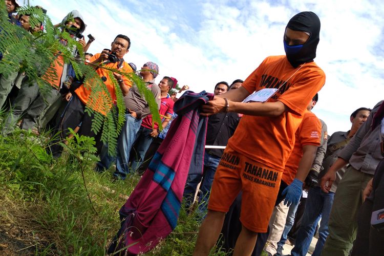 Pelaku memperagakan adegan tengah membuang mayat korban dalam pra rekonstruksi di Dusun Ciranggon III, RT 11, RW 03, Desa Ciranggon, Kecamatan Majalaya, Karawang, Senin (18/12/2017).
