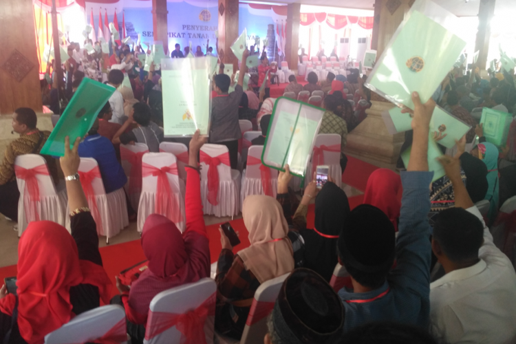 Warga mengangkat sertifikat tanah dalam pembagian sertifikat oleh Presiden Jokowi di Pendopo Pemkab Blitar, Jawa Timur, Kamis (3/1/2019).