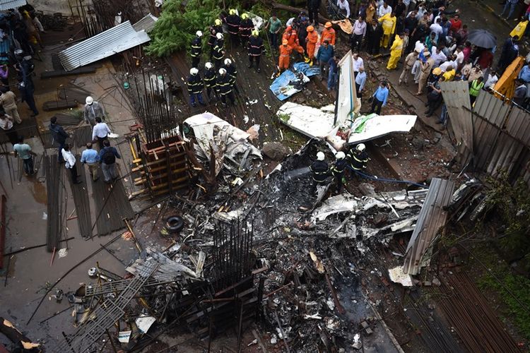 Petugas tim penyelamat memeriksa sisa-sisa badan pesawat yang jatuh dan terbakar setelah menabrak proyek konstruksi bangunan di Mumbai, India, Kamis (28/6/2018). Lima orang dilaporkan tewas akibat kecelakaan ini.