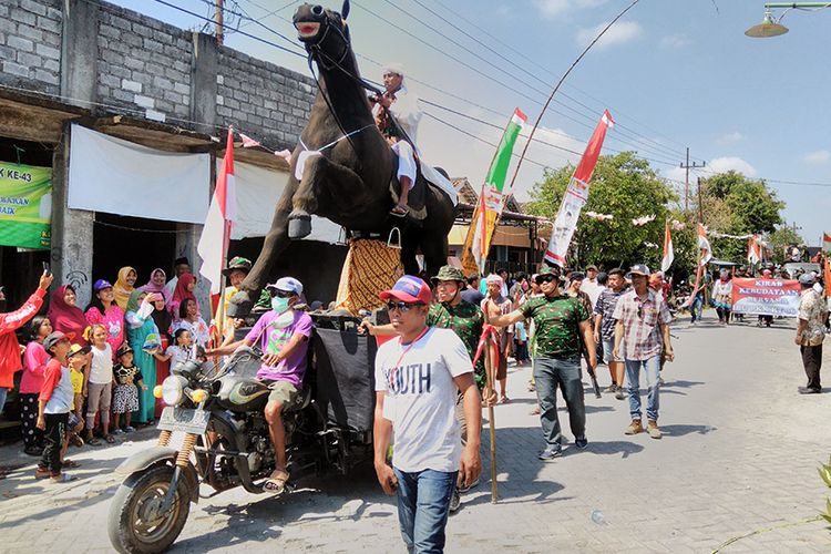 Replika kuda dengan ditumpangi orang yang ditampilkan dalam karnaval sedekah bumi di Desa Sumari, Gresik, Jatim, Minggu (19/8/2018).