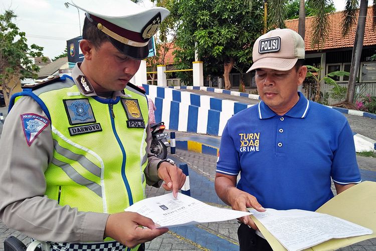 Aiptu Jailani (kanan) bersama dengan Ipda Darwoyo, saat berbincang di sela memberi pelatihan kepada pemohon SIM di halaman Satlantas Polres Gresik, Jumat (16/11/2018).