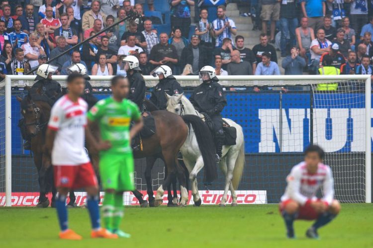 Polisi berjaga-jaga terhadap amukan suporter Hamburger SV seusai laga melawan Borussia Moenchengladbach, Sabtu (12/5/2018).