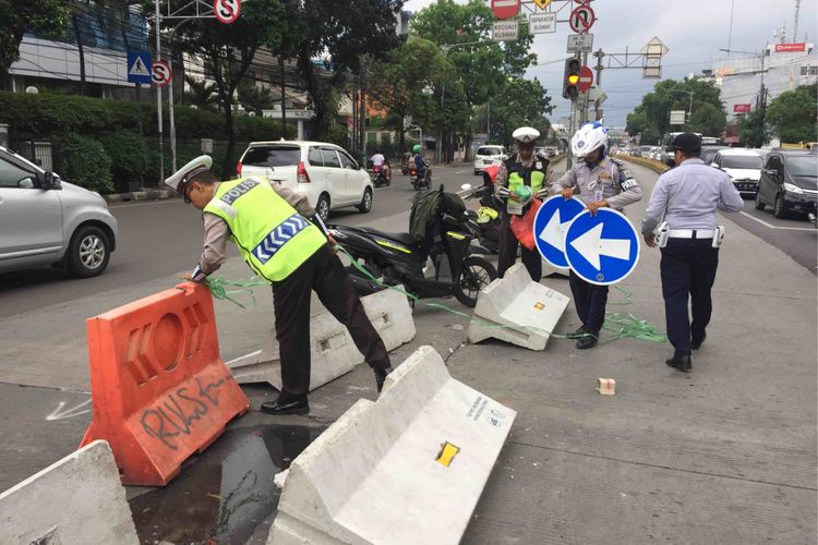 Sejumlah petugas kepolisian berusaha merapikan pembatas jalan di Simpang Duren Tiga, Pancoran, Jakarta Selatan yang dibongkar paksa puluha warga, Sabtu (19/5/2018).