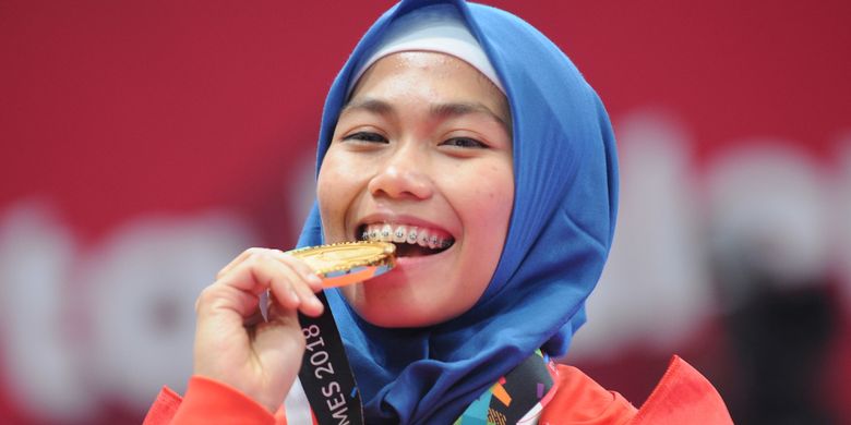 Taekwondoin putri Indonesia, Defia Rosmaniar menggigit medali emas yang diraihnya atas kemenangan di poomsae tunggal putri pertandingan Taekwondo di Asian Games 2018, di Jakarta Convention Center (JCC), Minggu (19/8). ANTARA FOTO/INASGOC/Sunyoto/inp/18