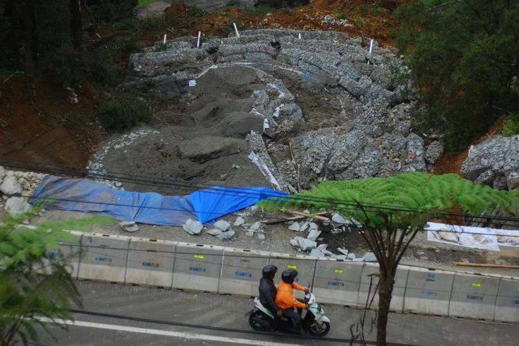 Seorang pengendara sepeda motor sedang melintas di lokasi longsor yang terjadi di perbatasan Bogor-Cianjur, tepatnya di kawasan Puncak Pass, Kamis (29/3/2018).