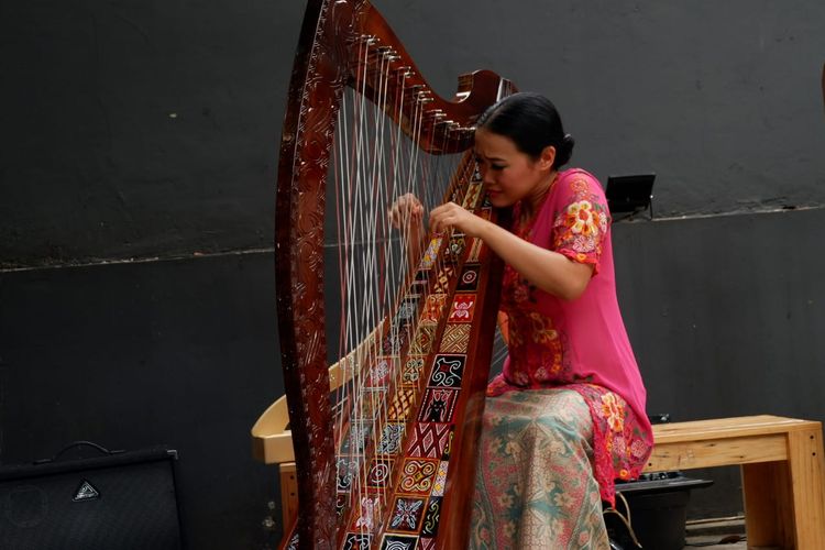 Musisi asal Bandung, Sisca, tengah memainkan harpa toraja. 