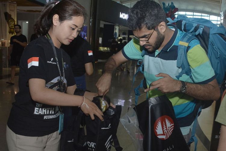 Relawan menukar kantong plastik yang digunakan pengguna jasa transportasi udara dengan tas kantong ramah lingkungan saat aksi Rampok kantong plastik, di kawasan Terminal Internasional Bandara I Gusti Ngurah Rai, Bali, Senin (18/3/2019). Aksi tersebut untuk mengurangi penggunaan kantong plastik di kawasan bandara.