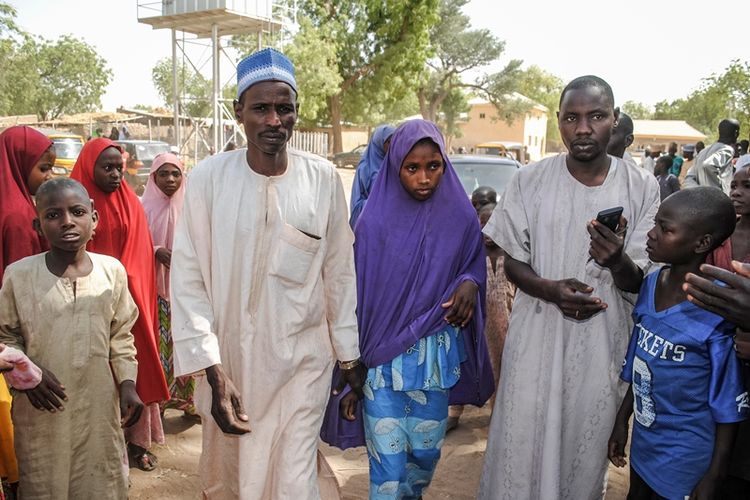 Seorang gadis yang dibebaskan oleh Boko Haram berjalan dengan ayahnya (kiri) di Dapchi, Nigeria, rabu (21/3/2018). (AFP)