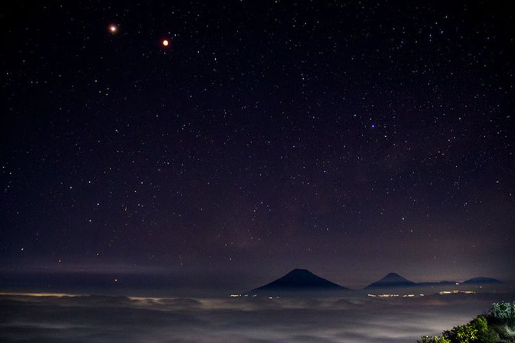 Pesona keindahan malam di langit barat Gunung Andong meliputi gerhana bulan dan planet mars, gemerlap bintang, dan Gunung Sindoro, Sumbing, serta Prau