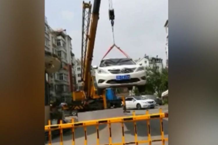 Mobil sedan putih yang angkat petugas menggunakan crane karena parkir sembarangan.