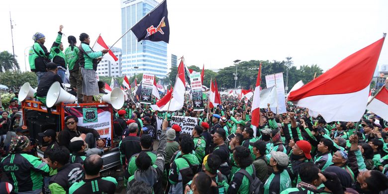 Sejumlah massa ojek online berunjuk rasa saat demo di depan Gedung DPR/MPR RI untuk berunjuk rasa menyampaikan aspirasinya, Senin (23/4/2018). Dalam demo ini para  pengemudi ojek online menuntut kenaikan tarif, Pengakuan legal, dan perlindungan hukum dan keadilan bagi ojek online.