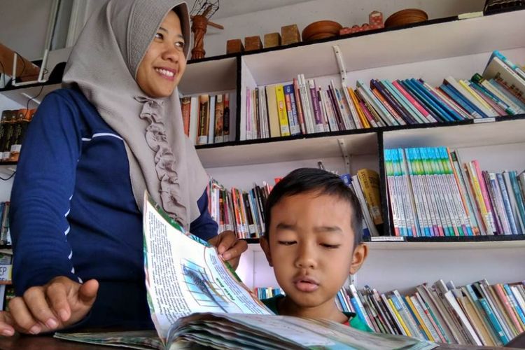 Pengunjung menemani anaknya membaca di Kafe Literasi, Desa Ujong Blang, Kecamatan Banda Sakti, Kota Lhokseumawe, Aceh, Minggu (15/7/2018).