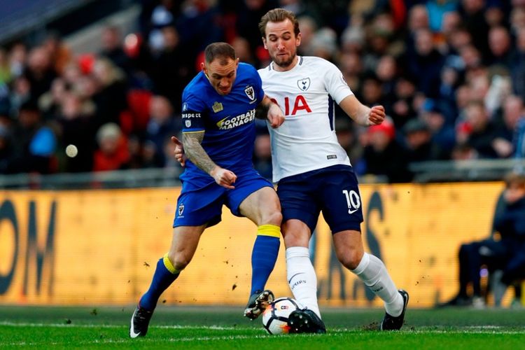 Striker Tottenham Hotspur, Harry Kane (kanan), berduel dengan bek AFC Wimbledon, Barry Fuller, dalam laga ronde ketiga Piala FA di Stadion Wembley, London, Inggris, pada Minggu (7/1/2018).