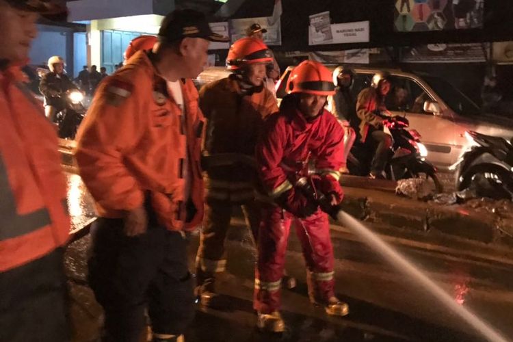 Petugas gabungan saling bahu membahu membersihkan lumpur di Jalan AH Nasution pasca banjir bandang yang terjadi Selasa (201/3/2018) sore.