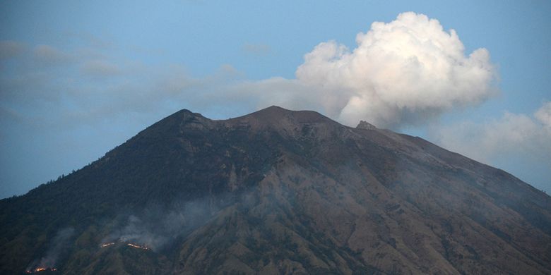 Asap dari api yang membakar hutan lereng Gunung Agung setelah terjadinya lontaran batu pijar dari kawah, terlihat dari Desa Tulamben, Karangasem, Bali, Selasa (3/7/2018). Pusat Vulkanologi dan Mitigasi Bencana Geologi mencatat terjadinya erupsi Gunung Agung dengan tinggi kolom abu mencapai 2.000 meter yang disertai lontaran batu pijar sejauh dua kilometer.