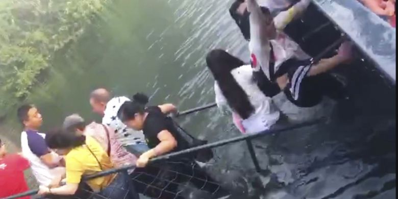 Dalam foto tersebut, terlihat turis yang berada di atas jembatan di Taman Dongjianghu, China, mendapat pertolongan setelah jembatannya ambruk Minggu (12/8/2018).