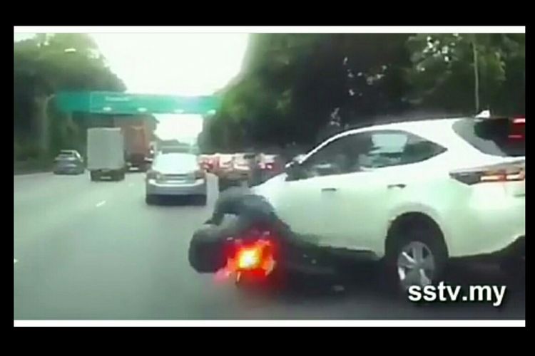 Seorang pengendara motor yang menabrak mobil yang berpindah lajur secara tiba-tiba. 