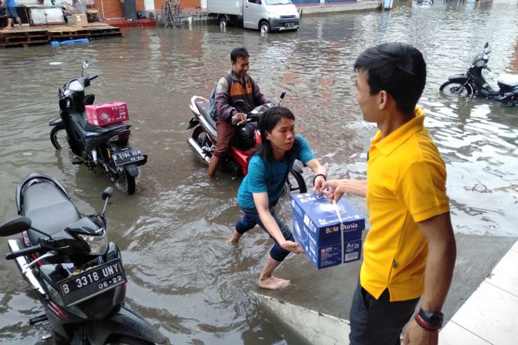 Aktivitas bekerja di tengah banjir di ruko Grosir Tekstil, Mangga Dua, Jakarta Utara, Selasa (5/3/2019)