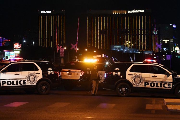 Police form a perimeter around the road leading to the Mandalay Hotel (background) after a gunman killed at least 50 people and wounded more than 200 others when he opened fire on a country music concert in Las Vegas, Nevada on October 2, 2017. 
Police said the gunman, a 64-year-old local resident named as Stephen Paddock, had been killed after a SWAT team responded to reports of multiple gunfire from the 32nd floor of the Mandalay Bay, a hotel-casino next to the concert venue. / AFP PHOTO / Mark RALSTON