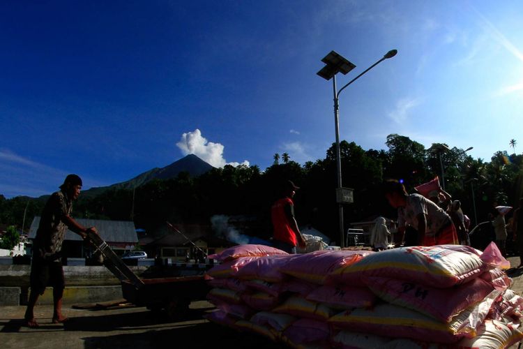 Aktifitas bongkar muat di dermaga Pelabuhan Ulu Siau, Kabupaten Sitaro, Sulut dengan latar belakang Gunung Api Karangetang yang kawahnya terus mengeluarkan asap vulkanik.