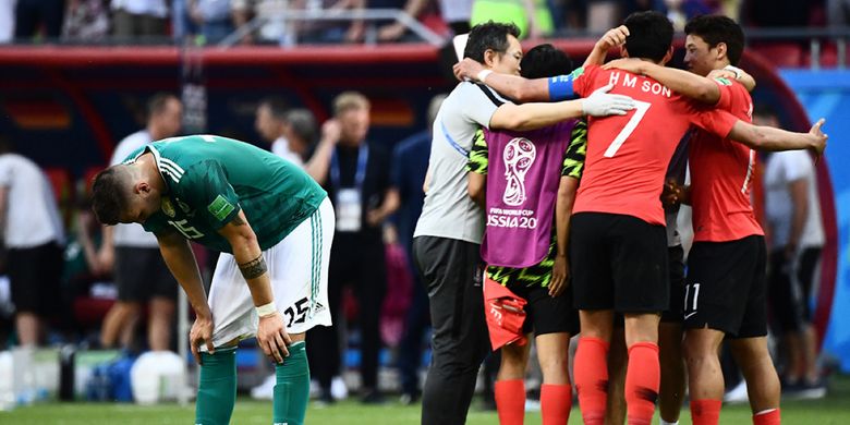 Pemain Jerman Niklas Suele (kiri) bereaksi dengan latar belakang pemain Korea Selatan yang sedang merayakan kemenangan dalam laga penyisihan Grup F Piala Dunia 2018 di Kazan Arena, Kazan, Rabu (27/6/2018). Sang juara bertahan Jerman terdepak dari ajang Piala Dunia usai ditaklukkan Korea Selatan dengan skor 2-0.
