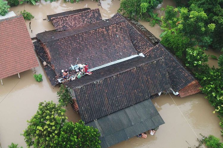 Sejumlah warga menyelamatkan diri di atas atap rumah saat terjadi banjir di Desa Purworejo, Pilangkenceng, Kabupaten Madiun,  Jawa Timur, Rabu (6/3/2019). 