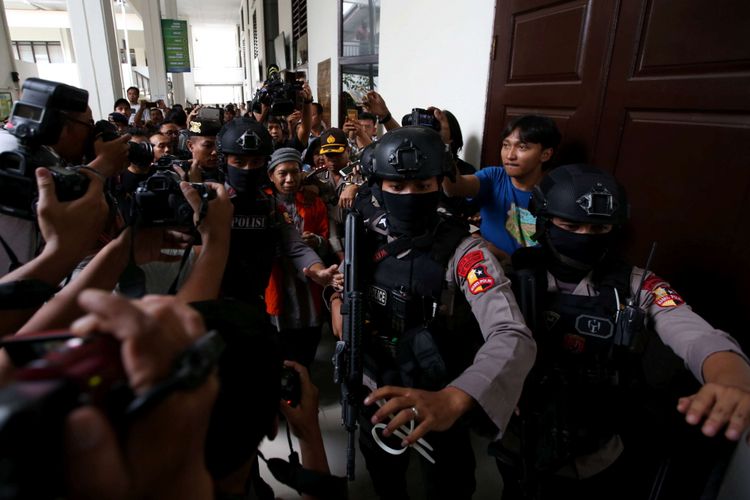 Terdakwa kasus teror bom Thamrin Aman Abdurrahman (memakai rompi oranye di tengah) usai menjalani sidang di Pengadilan Negeri Jakarta Selatan, Jumat (18/5/2018). 
