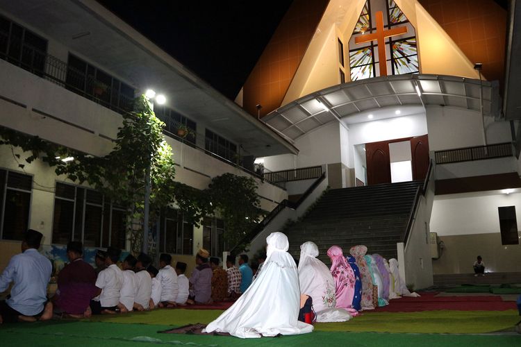 Para siswa dan guru MI Islamiyah menggelar shalat Maghrib di komplek SD Kristen Petra Jombang, (27/5/2019) malam.
           