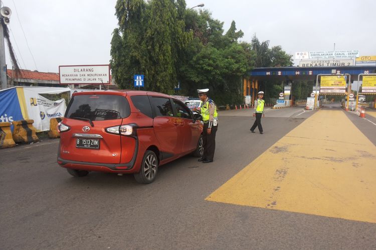 Salah satu mobil berpelat ganjil yang diminta putar balik di depan gerbang tol Bekasi Timur arah Jakarta pada hari pertama penerapan skema ganjil genap Tol Cikampek, Senin (12/3/2018).