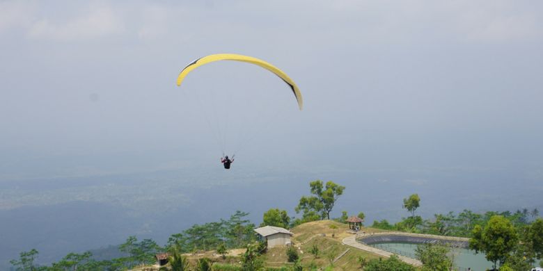 Seorang Atlet Paralayang Terbang di Atas Embung Batara Sriten, Nglipar, Gunungkidul