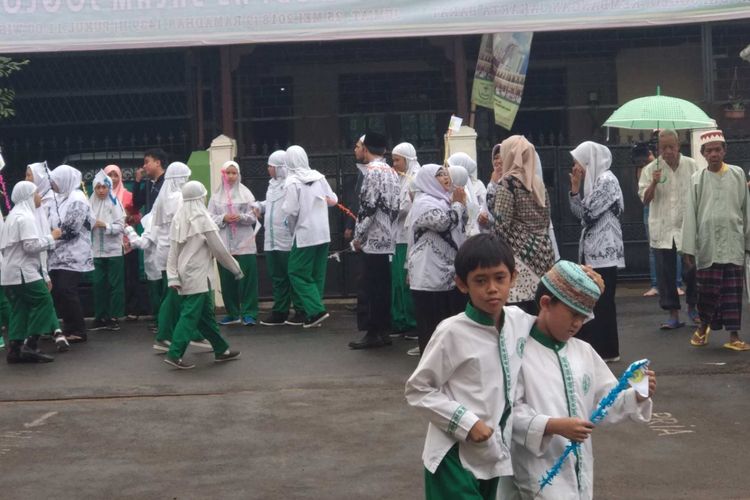 Puluhan anak-anak SD As-Salam Joglo rela berhujan-hujanan di depan sekolah mereka, Jumat (25/5/2018). Mereka menunggu kedatangan Gubernur DKI Jakarta Anies Baswedan yang akan meresmikan sekolah dan masjid mereka yang baru direnovasi.