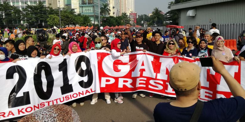 Sejumlah warga tampak berjalan kaki dengan spanduk sembari memakai kaus dan kaus #2019GantiPresiden di Bundaran HI, Jakarta, Minggu (29/4/2018).