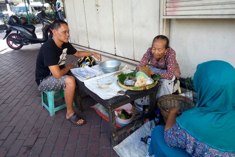 Seorang pembeli saat menunggu Mbah Satinem menyiapkan lupis. 