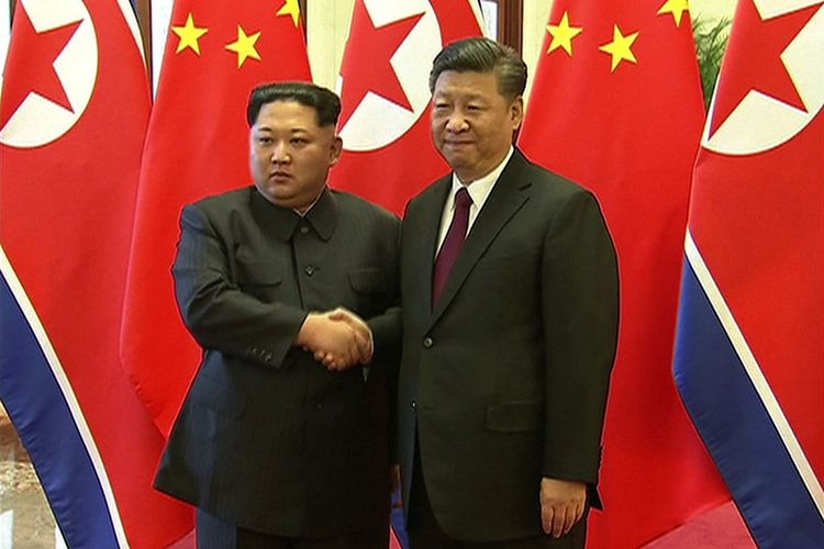 Gambar ini diambil dari rekaman video yang dirilis oleh China Central Television (CCTV) pada Rabu (28/3/2018) menunjukkan Presiden China Xi Jinping (kanan) dan pemimpin Korea Utara Kim Jong Un berjabat tangan selama pertemuan mereka di Beijing pada Selasa (27/3/2018). (CCTV/AFP)