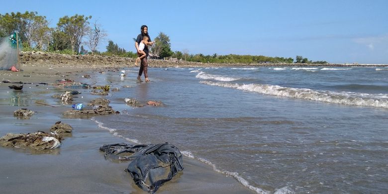 Wisatawan bermain disela sampah di kawasan wisata Pantai Ujong Blang, Desa Ujong Blang, Kecamatan Banda Sakti, Kota Lhokseumawe, Aceh, Minggu (13/1/2019).