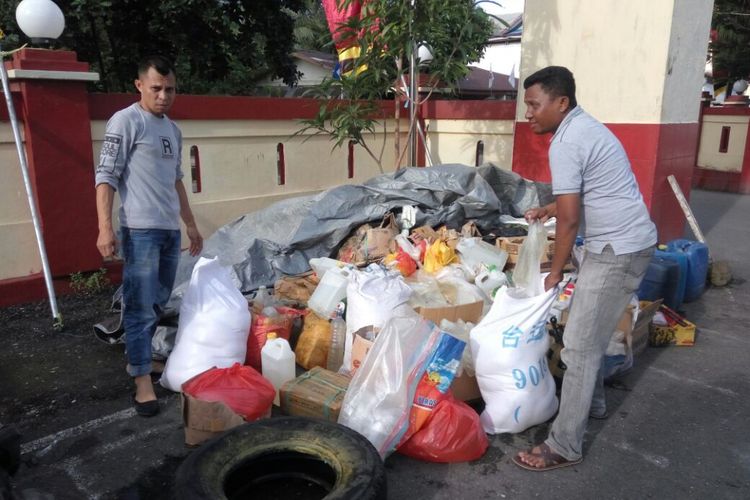 Sejumlah anggota Polres Pulau Ambon sedang mengumpulkan ribuan liter miras  untuk dimusnahkan ke dalam selokan di depan Mapolres Pulau Ambon, Senin (10/7/2017)/Kontributor Ambon, Rahmat Rahman Patty   