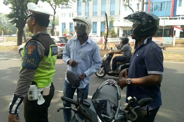 Seorang petugas polisi lalu lintas tangerang selatan yang tampak kebingungan komunikasi dengan pengendara WNA Arab yang di tindak saat operasi patuh jaya 2019